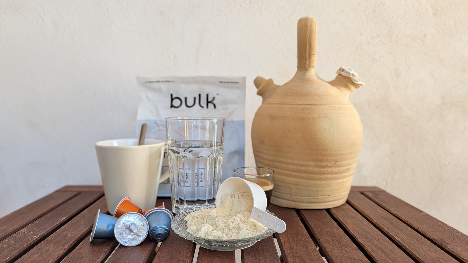 Polvo de proteína junto a bote de suplemento en mesa exterior, luz natural